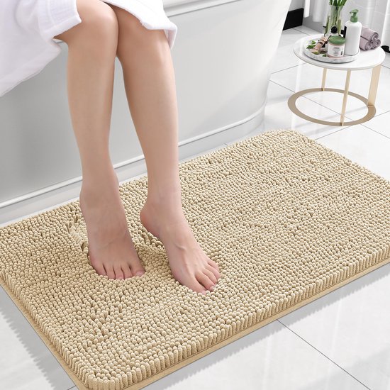 Beige badmat met hoge pool, met blote voeten erop bij een badkuip.