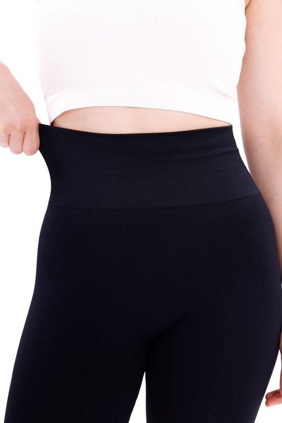 Detailopname van de hoge, geribbelde tailleband van een zwarte sportlegging.