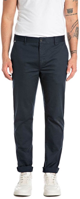 Vue de face d'un modèle portant un pantalon chino bleu foncé avec ourlets retroussés et des baskets blanches.
