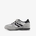Grijze sneaker met zwarte zigzagstrepen, klittenbandsluiting en zwarte accenten.