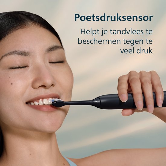 Aziatische vrouw met gesloten ogen en tandenborstel in de mond, achtergrond met lucht.