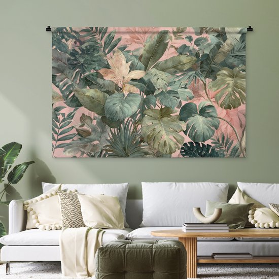 Een tropische bladerenprint in groen en roze op een wandkleed, hangend boven een witte bank in een groen geverfde kamer.