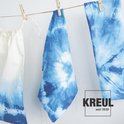 Trois pièces de tissu à imprimé batik bleu sèchent sur une corde à linge.