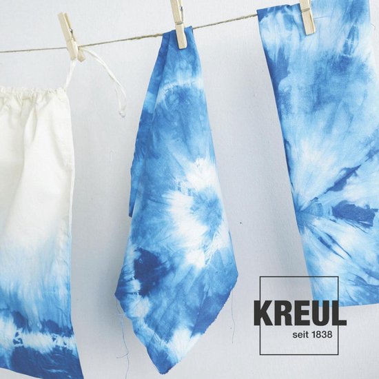 Trois pièces de tissu à imprimé batik bleu sèchent sur une corde à linge.