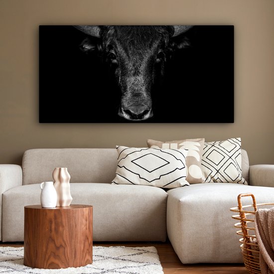 Toile noir et blanc avec un gros plan d'une tête de taureau, placée sur un fond sombre.