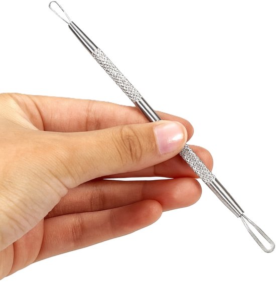 Hand die een zilveren comedonenlepel vasthoudt met gekartelde grip en lussen aan beide uiteinden.