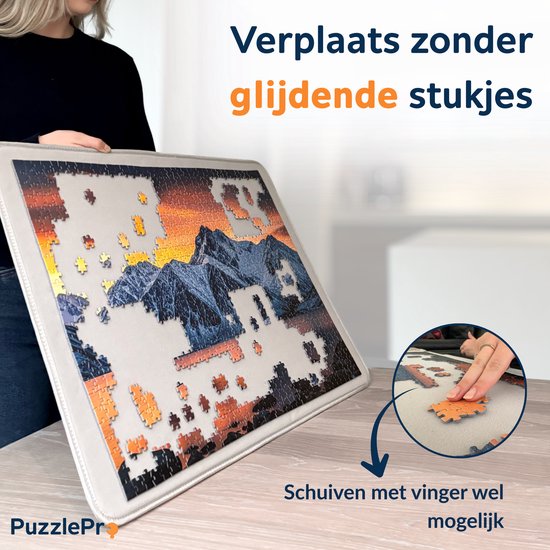Een vrouw verplaatst een puzzel van 1000 stukjes met een berglandschap met een PuzzlePro mat. Afmetingen 73x53cm.