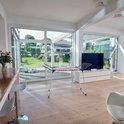 Grand étendard pliable blanc et bleu, placé dans un salon moderne avec de grandes fenêtres et vue sur un jardin.