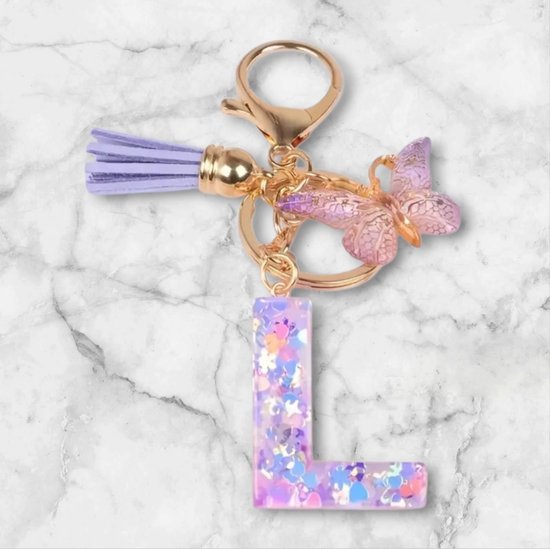 Paarse letter L sleutelhanger met vlinder en paarse kwast. Gevuld met glitters.