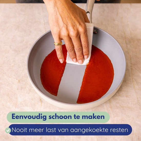 Hand met gouden ring veegt rode saus uit een grijze koekenpan met witte rand.
