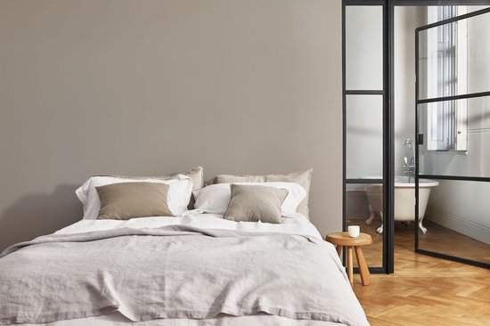 Slaapkamer met kingsize bed, linnen beddengoed, kussens en een glazen deur naar een bad.
