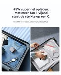 Een reiskoffer met de grijze GaN-oplader, een horloge en kleding, en een andere koffer met een laptop en kabels.