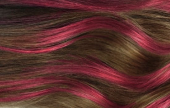Donkerbruin haar met gedurfde frambooskleurige highlights, golvend.