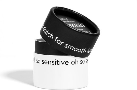 Zwarte en witte verpakking met tekst. Zwart deksel met 'lekker' en 'dutch for smooth luscious'.