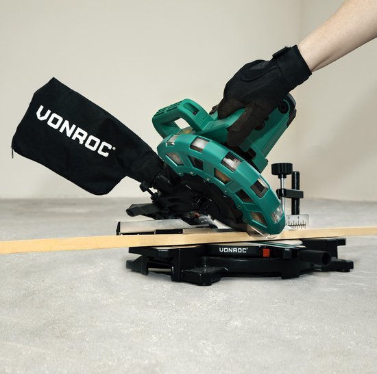 Hand met handschoen bedient VONROC afkortzaag, zaagt een houten balk.