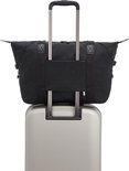 Sac Kipling ART M noir avec poignées et passant pour trolley, sur une valise argentée.