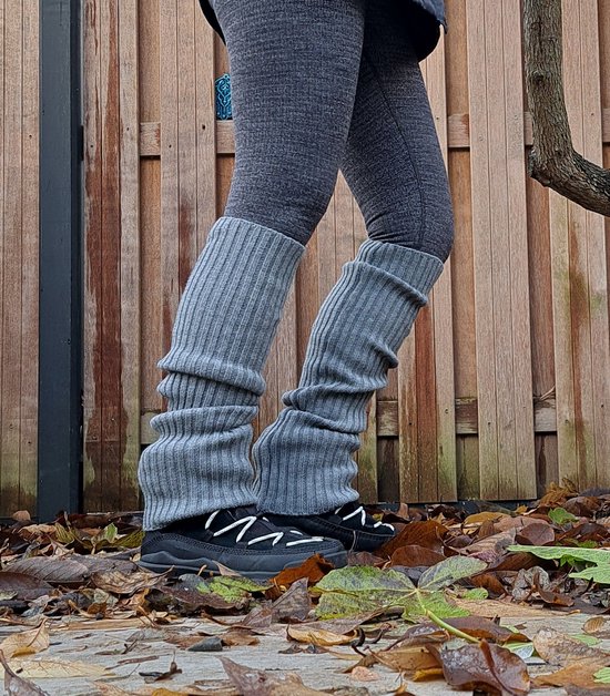 Model draagt grijze, opgerolde beenwarmers met grijze legging en sneakers.