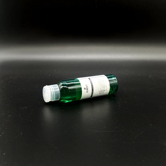 Fles met groene schoenreiniger van First Amsterdam, liggend op een zwarte achtergrond.