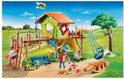 Playmobil speeltuin met groen speelhuis, klimmuur, glijbaan, schommel en figuren.