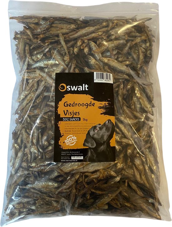 Een doorzichtige zak Oswalt gedroogde visjes voor honden, 1kg. Zwarte hond kijkt omhoog naar het etiket.