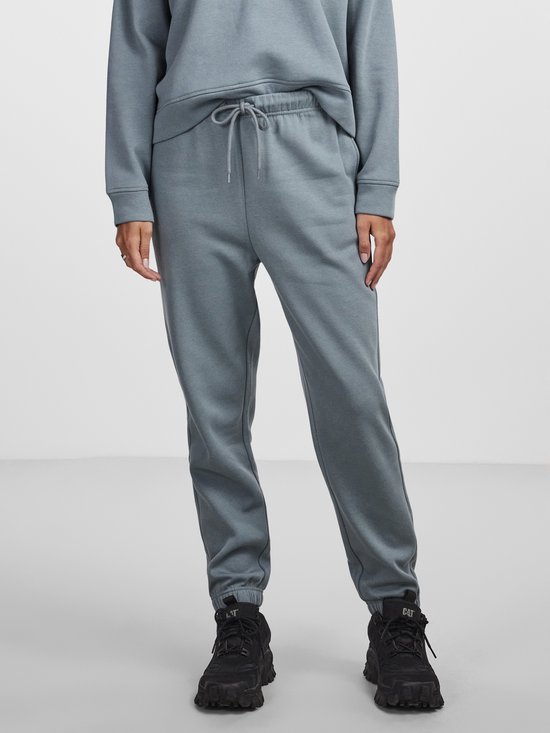 Model draagt een petrolkleurige joggingbroek en stoere zwarte laarzen.