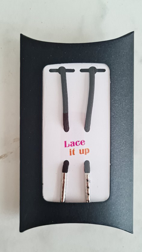 Zwarte veters met zilveren nestels op zwarte verpakking. Tekst 'Lace it up'.