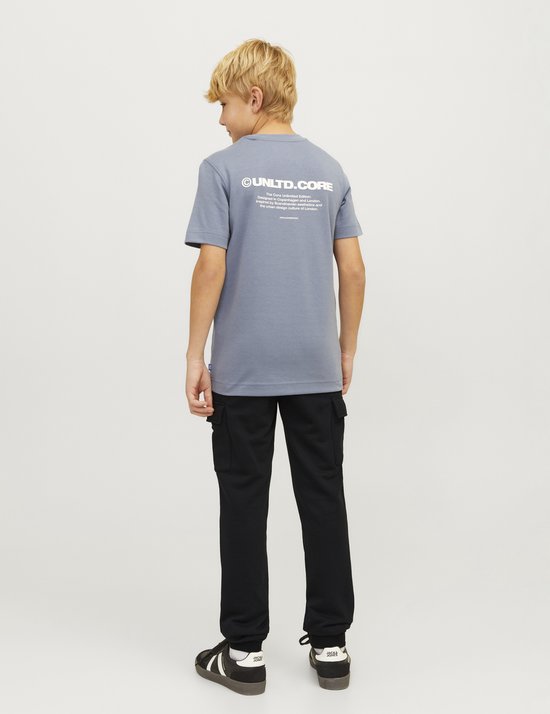 Jongen in grijze t-shirt met tekst en zwarte cargobroek, staand.