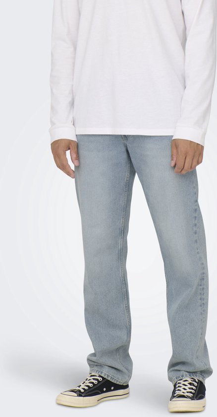 Homme portant un t-shirt blanc à manches longues et un jean bleu clair.