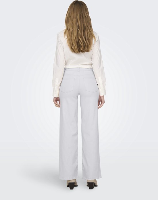 Vrouw in witte blouse en lichtgrijze wide-leg jeans, van achteren gezien.
