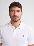 Een witte polo met een klein logo op de linkerborst, gedragen door een man.