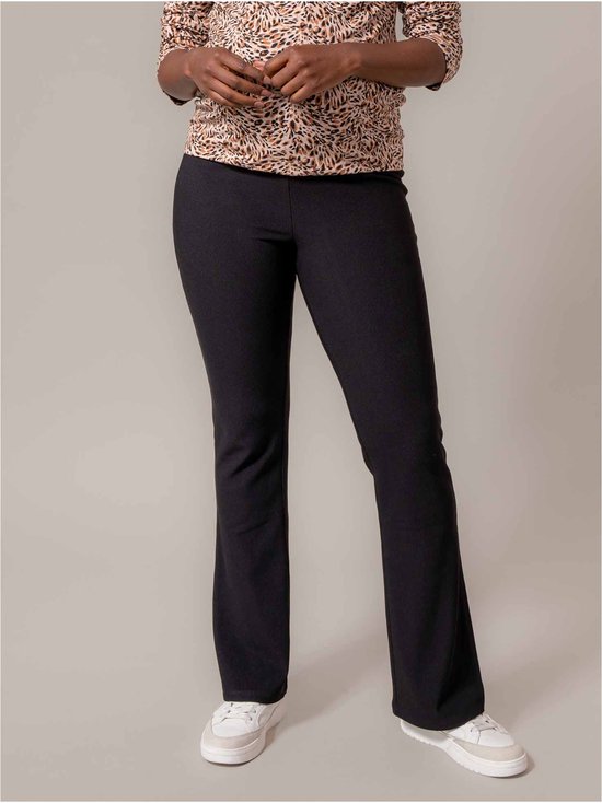 Model draagt een zwart-bruine dierenprint top met driekwart mouwen en zwarte bootcut broek.