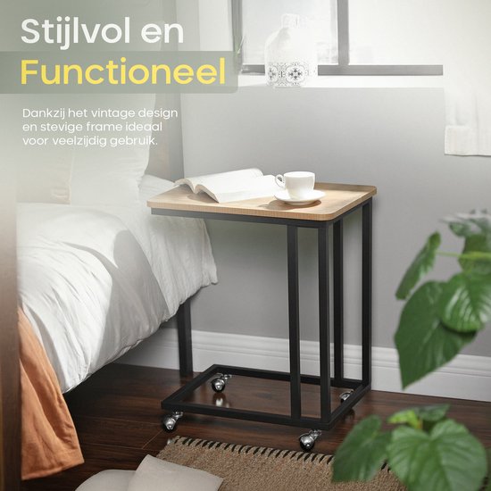Stijlvol en functioneel bijzettafeltje met houtnerf blad en zwart metalen frame met wielen, naast een bed.