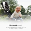 Een kind in een zwarte buggy in een park.