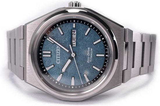 Zilverkleurig Citizen Eco-Drive Titanium horloge met een blauwgroene wijzerplaat, datumaanduiding en metalen band.