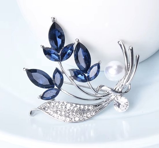 Zilverkleurige broche met blauwe kristallen bladeren, parel en strass steentjes.