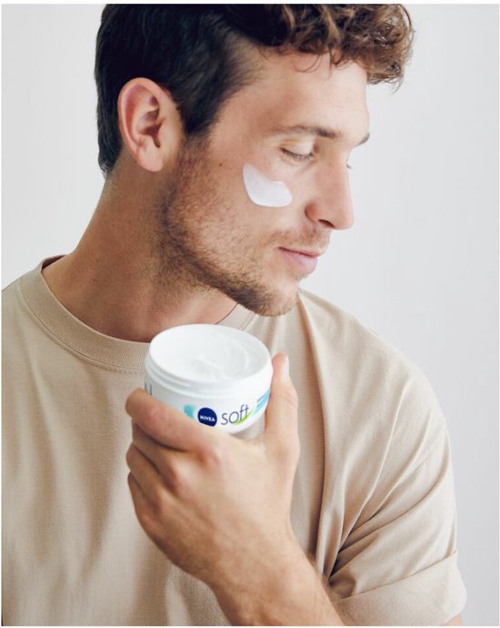 Man met korte bruine haren, in beige t-shirt, smeert NIVEA Soft crème op gezicht.