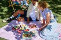 Een groep mensen geniet van een picknick in het park met diverse Mepal servies in pastelkleuren.