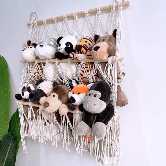Système de rangement blanc en macramé avec bâtons en bois, rempli de peluches variées.