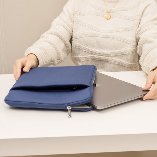 Donkerblauwe laptoptas op een tafel. Een laptop wordt eruit gehaald.