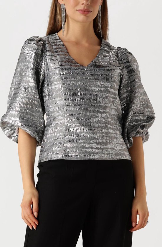 Model draagt zilveren blouse met pofmouwen en V-hals, met horizontale textuur.