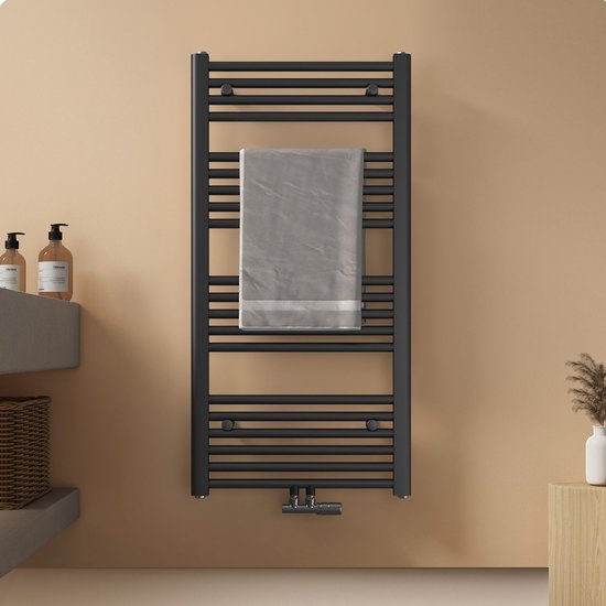 Zwarte handdoekradiator met een grijze handdoek erop, aan een zandkleurige muur.