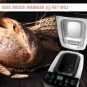 Gouden, versgebakken brood met een knapperige korst, naast een open broodmachine met een zilveren interieur.