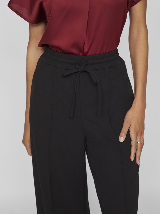 Close-up van de tailleband van een zwarte broek met trekkoord en naaddetails.