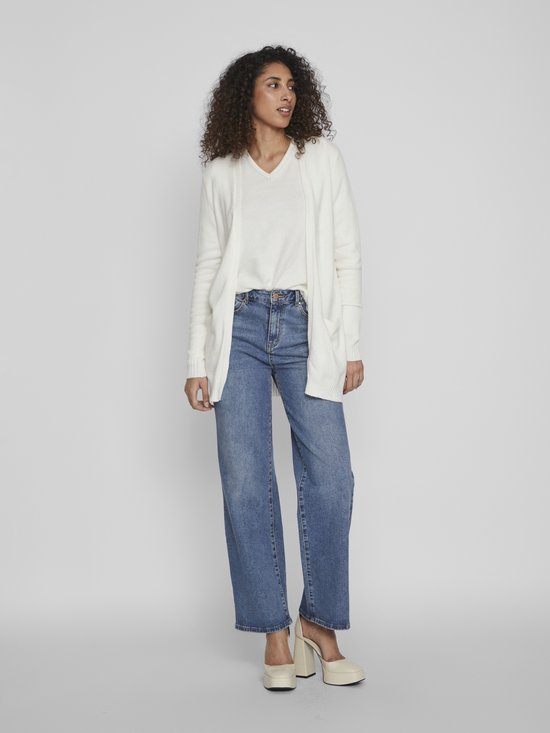 Een witte VILA open gebreide cardigan met lange mouwen, gedragen door een vrouw met een witte top en spijkerbroek.