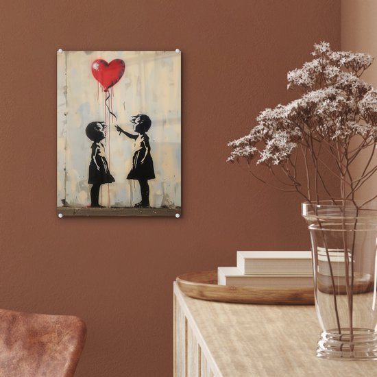 Street art-glasafbeelding van twee kinderen die naar een rode hartballon reiken, hangend aan een bruine muur.