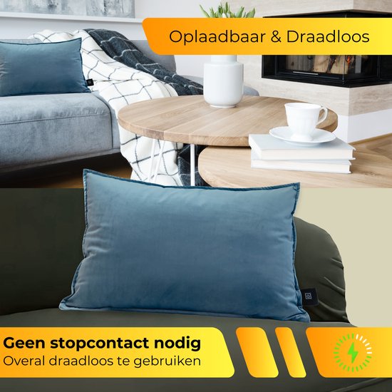 Oplaadbaar en draadloos warmtekussen in blauwe fluwelen stof, afgebeeld in een woonkamer.