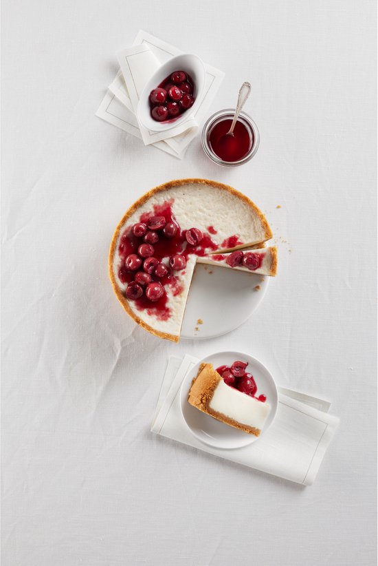 Gecentreerde taart met kersen, met twee punten, naast een punt cheesecake.