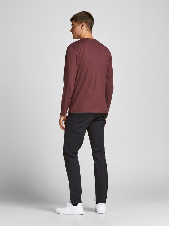 Man met bordeauxrode longsleeve en zwarte chino.