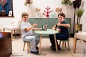 Twee jongens zitten aan een tafel en wijzen naar een groene Skip-Bo draagtas.
