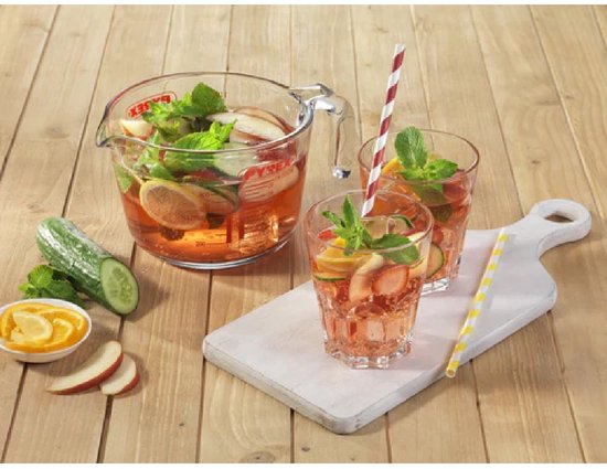 Glazen Pyrex maatbeker met een roze drank, geserveerd met fruit en munt. Twee glazen, komkommer en citroen erbij.